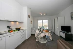 a kitchen with white cabinets and a table in a room at Via al Chioso in Lugano +8 photos