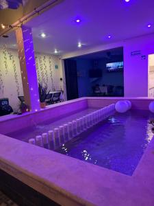 a swimming pool in a room with purple lighting at Casa Faustos in Mérida