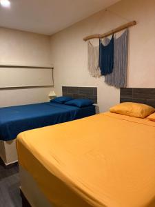two beds in a room with yellow and blue sheets at Casa Faustos in Mérida +33 photos