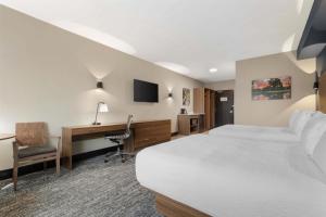 a hotel room with a bed and a desk and a computer at Best Western Plus Neepawa Hotel in Neepawa