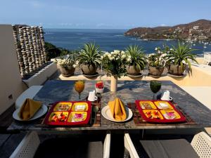 a table with plates of food on top of a balcony at Tentaciones Boutique Hotel - Ocean View & Private Pools - Adults Only in Zihuatanejo