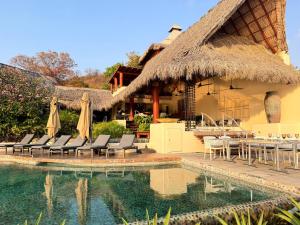a house with a thatched roof and a swimming pool at Tentaciones Boutique Hotel - Ocean View & Private Pools - Adults Only in Zihuatanejo