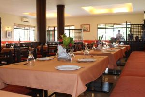 a row of tables in a restaurant with plates and glasses at The International Centre Goa in Panaji