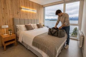 a man standing next to a bed with a bag at B612 Bariloche in San Carlos de Bariloche