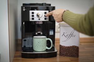 a person is pointing at a coffee maker with a cup at Appartement Swing in Mittelberg