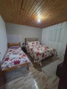 a bedroom with two beds and a wooden ceiling at Sítio jaguary in Camanducaia