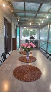 a table with a vase with pink flowers on it at Spacious & Sun-Filled Highlands Retreat in Moss Vale