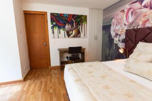 a bedroom with a bed and a desk and a painting at Libertg Hotels Medellin in Copacabana