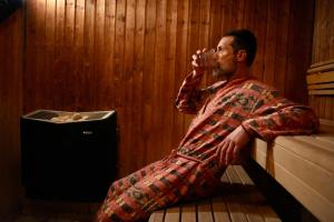 a man sitting on the floor drinking from a cup at Manon Les Suites Guldsmeden in Copenhagen