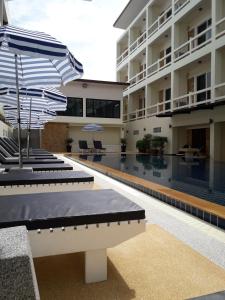 una piscina del hotel con sombrillas en el patio en Phangan Pearl Villa, en Haad Rin