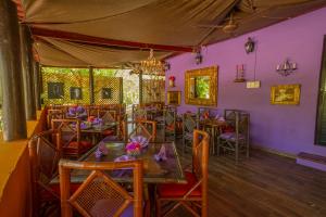 ein Restaurant mit lila Wänden und Holztischen und -stühlen in der Unterkunft The Pickled Onion Hotel & Restaurant Uxmal in Santa Elena