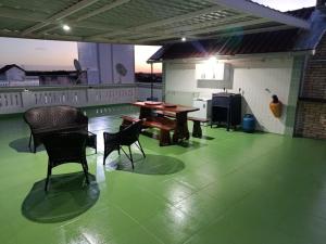a patio with a table and chairs on a green floor at Cobertura Encantadora Conde PB in Conde