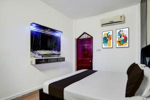 a white bedroom with a bed and a tv at Hotel O Vishal Residency in New Delhi