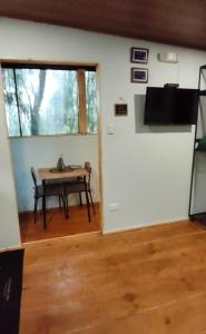 a living room with a table and a door with a television at La Casita Verde in Boquete