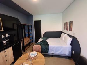 a small bedroom with a bed and a table at One Studios Indaiatuba in Indaiatuba