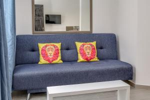 a blue couch with two yellow and red pillows at Valentina Suites by Las Flores Vacation Rentals in Playa del Carmen