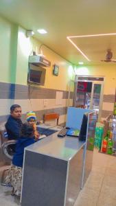 a man and a child sitting at a desk at Soni Hotel in Hanumāngarh