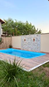 a swimming pool in a backyard with a brick wall at Loft Brisa de Búzios in Búzios