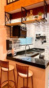 a kitchen with a counter with two chairs and a sink at Loft Brisa de Búzios in Búzios