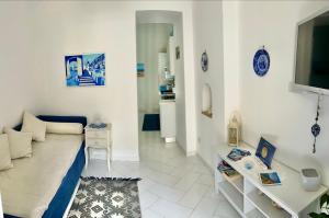 a white living room with a couch and a tv at Santiago vacation home in Positano in Positano