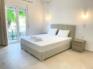 a bedroom with a bed with white sheets and a window at Κωνσταντίνος Έλενα Studios in Pefki