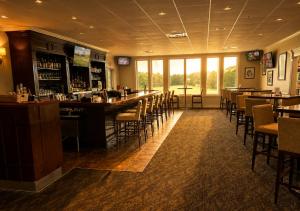 a bar in a restaurant with tables and chairs at The Cape Club Golf Resort in Falmouth