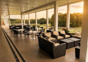 a restaurant with couches and tables and chairs and windows at The Cape Club Golf Resort in Falmouth