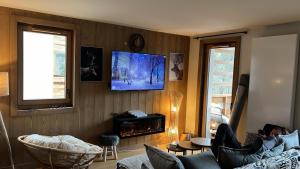 a living room with a couch and a tv on the wall at L'Altima Megève in Megève