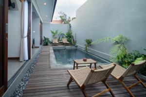 a swimming pool in a house with chairs and a table at Dahayu Villa Ubud in Ubud