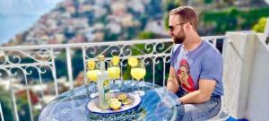 a man sitting on a balcony with a table with drinks at Santiago vacation home in Positano in Positano
