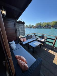 a boat deck with couches and tables on the water at Florea Cottage in Ulcinj