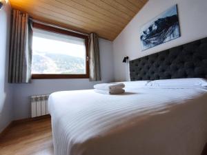 a bedroom with a large bed with a large window at AC Apartaments Sol Tarter in El Tarter