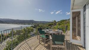 a patio with a table and chairs on a balcony at The Harbour Masters Cottage for Two in Tairua
