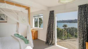a bedroom with a bed and a large window at The Harbour Masters Cottage for Two in Tairua +8 photos