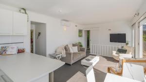 a living room with a couch and a tv at The Harbour Masters Cottage for Two in Tairua