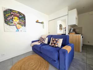 a blue couch in a living room with a kitchen at Studio *Sérénité* in Villejuif