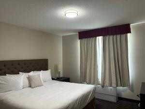 a bedroom with a white bed with a window at Ramada by Wyndham Estevan in Estevan