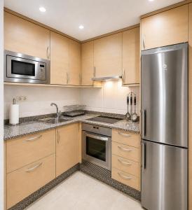 a kitchen with wooden cabinets and a stainless steel refrigerator at Apartamento vistas al mar in Viveiro