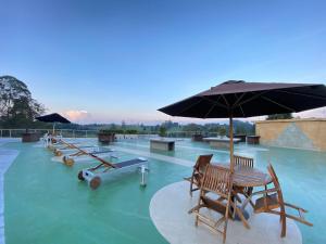 a pool with chairs and an umbrella in the water at Hotel Rioverde Living Suites in San Antonio de Pereira