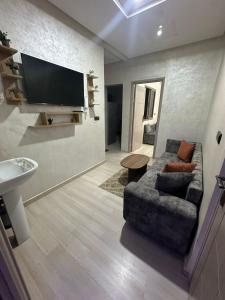 a living room with a couch and a flat screen tv at شقة مفروشة للكراء اكادير للعائلات فقط in Agadir