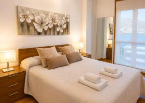 a bedroom with a large bed with two towels on it at Apartamento vistas al mar in Viveiro