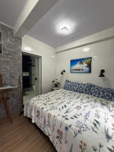 a bedroom with a bed with a floral bedspread and a desk at vista mar suite luxo in Angra dos Reis