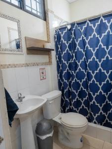 ein Badezimmer mit Toilette, Waschbecken und blauem Duschvorhang in der Unterkunft Villa de María in Guayaquil + 97 Fotos