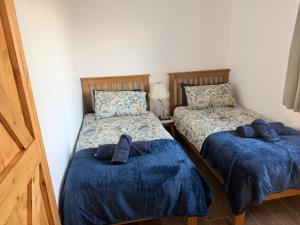 two beds in a bedroom with blue comforters on them at The Cottage in Ballaghaderreen