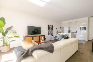 a living room with a white couch and a kitchen at Lux 2BR Apt on Hindmarsh SQ-Pool-Gym-Parking in Adelaide