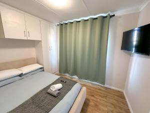 a small room with a bed and a green curtain at Silwood Heights Flatlet in Eerste River in Faure