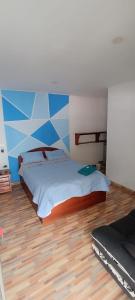 a bedroom with a bed and a blue and white wall at Hotel el CRISTAL Muzo in Muzo