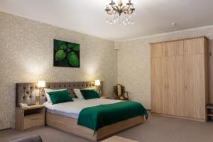a bedroom with a bed with green sheets and a chandelier at Elit Garden Hotel in Kamianets-Podilskyi
