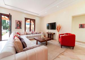 a living room with a couch and a red chair at Luxury villa in Azib Oulad Lâdem