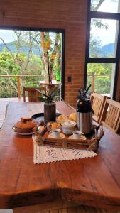 a wooden table with a tray of food on it at Casa Chalé dos Pinhas - Chalé Romântico e Aconchegante - Hidromassagem - Lareira - Vista da Montanha - Próximo a Campos do Jordão in Santo Antônio do Pinhal